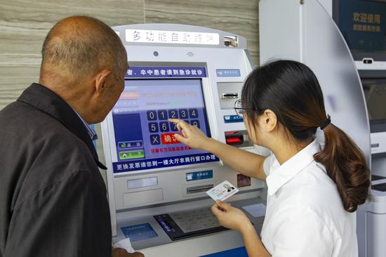 服務(wù)人員通過掛號自助機為老人預(yù)約專家。潘迎霞 攝